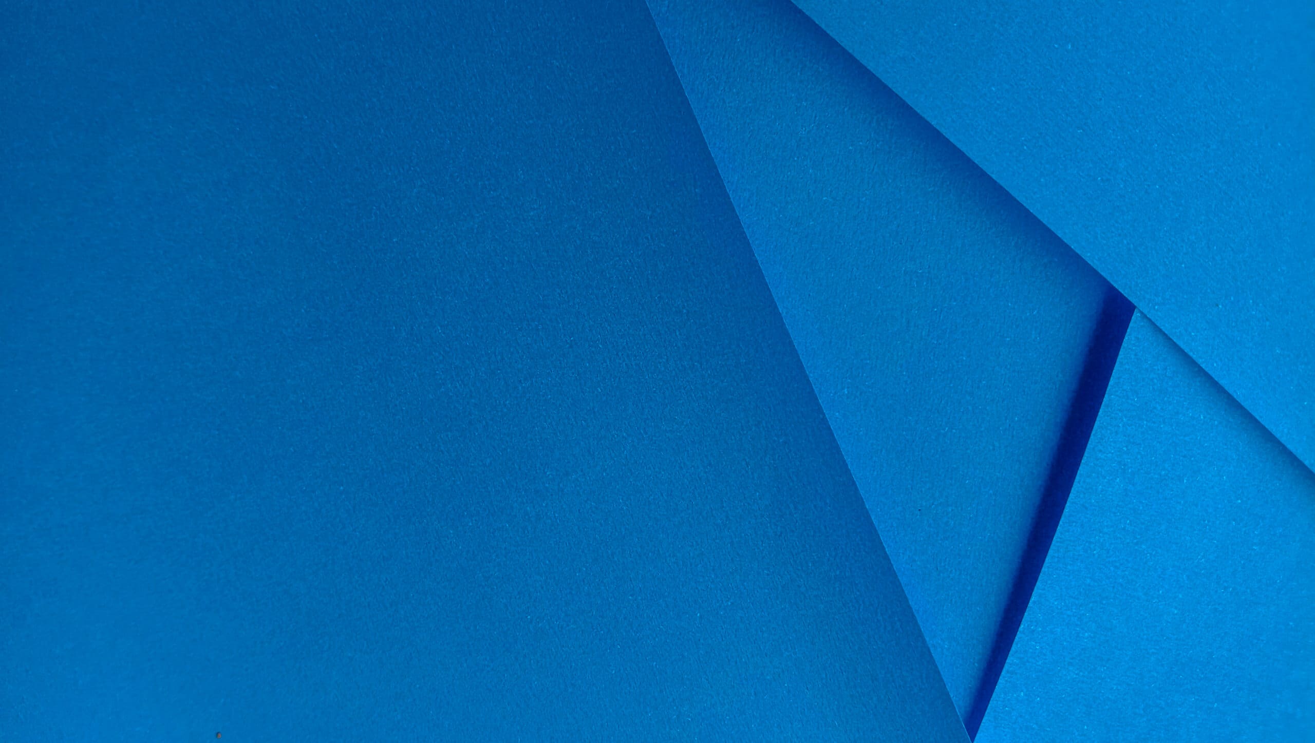 Abstract close-up of overlapping blue paper sheets, creating geometric shapes and shadows with various shades of blue—reminiscent of the clean lines often seen in new bathrooms designed by a skilled builder.